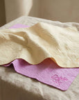 Absorbent Dog Towel, two dog towels on a table. one is pink and the other is yellow, towels are a shammy cloth style