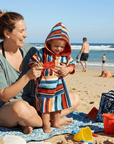 Woman and baby on the beach, with the baby wearing a colorful hooded towel.