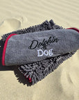 Close-up detail of the grey Dolphin & Dog fast drying towel showing the logo and soft material texture.