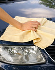 Hand using a super absorbent chamois towel to dry a wet car bonnet after washing. car shammy.