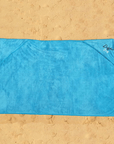 dog towel laid out on the beach showing it full size. corner pockets for hands to be placed