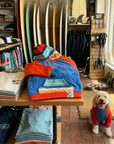a dog hoodie on display in a surf ship, the dog hoodie is brightly coloured and shows a pockets and hood design,