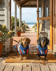 Two Dachshunds in custom dog towels and woman in a matching hooded towel at a beach house doorway.