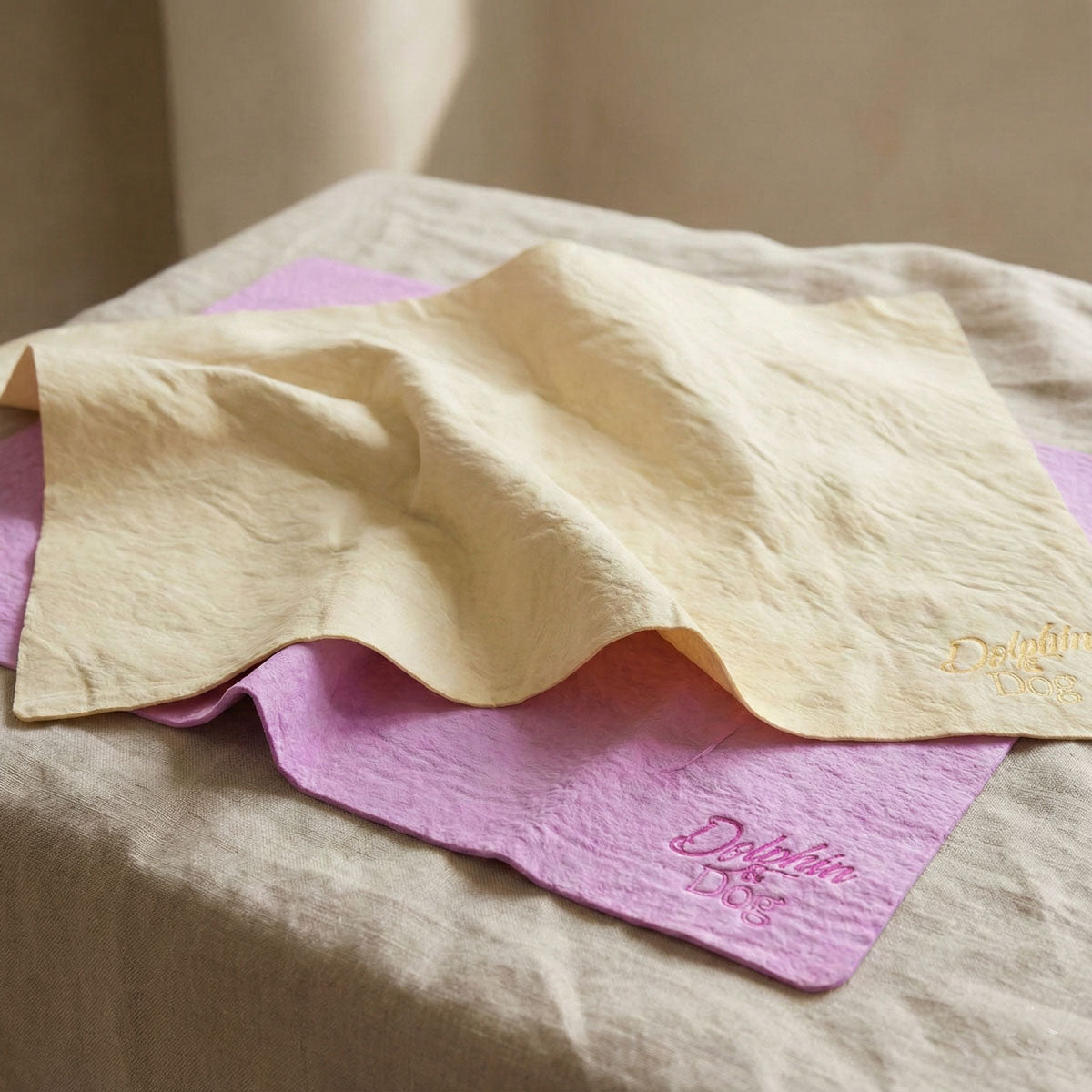 Absorbent Dog Towel, two dog towels on a table. one is pink and the other is yellow, towels are a shammy cloth style