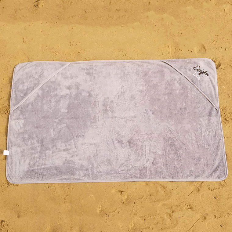 Dog towel spread out on the beach, showing its full size and corner hand pockets.