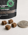 Small air-dried dog training treats shown beside an Australian 20 cent coin for size comparison.
