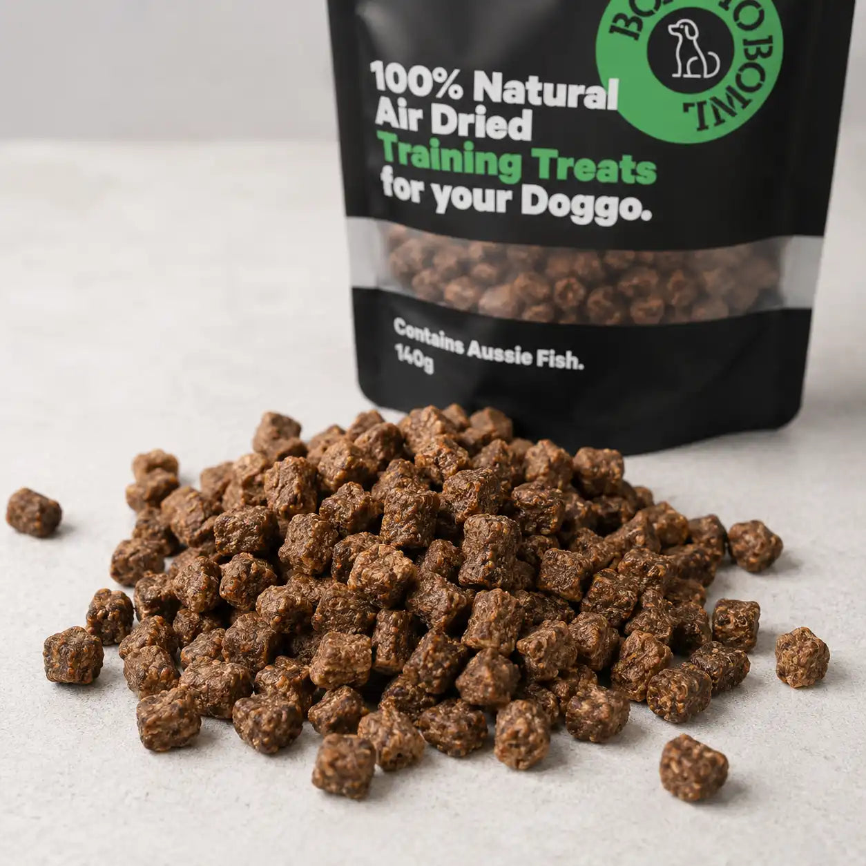 Close-up of natural air-dried fish dog training treats scattered in front of a Boat To Bowl treat bag.