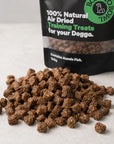Close-up of natural air-dried fish dog training treats scattered in front of a Boat To Bowl treat bag.