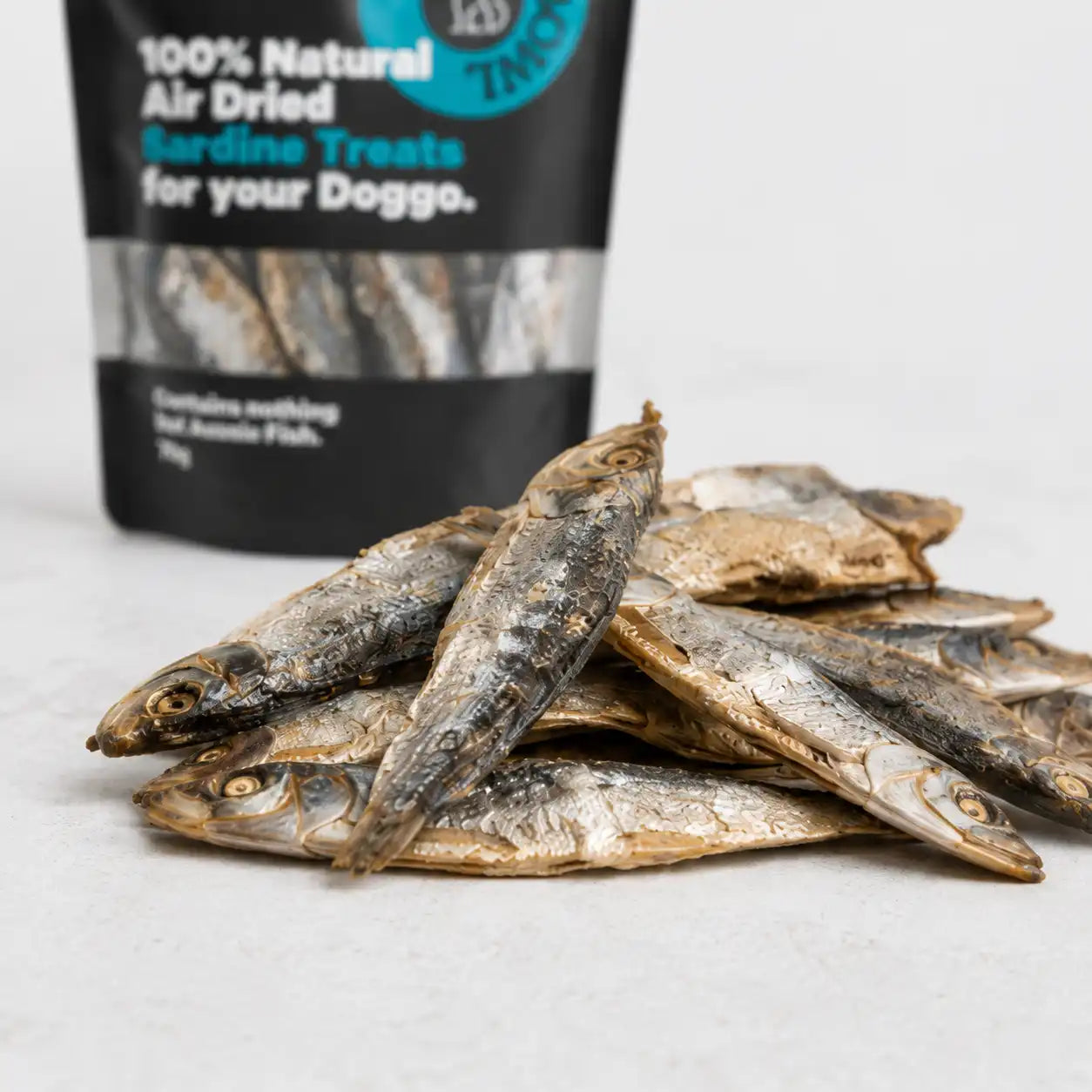 Close-up of whole air-dried sardine dog treats with the Boat To Bowl sardine treat bag in the background.