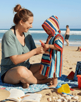 Woman and child on a beach with colorful kids beach towel, sand toys, and ocean view.