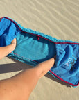 Dolphin & Dog fast drying dog towel held open on the beach, showing hands in the corner pockets for easy drying.