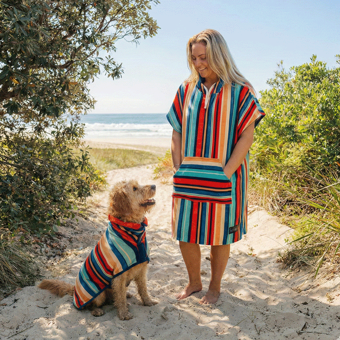women and dog wearing matching drying robes at the beach, women has a hooded towel and dog a wearable hooded dog towel. 
