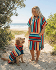 women and dog wearing matching drying robes at the beach, women has a hooded towel and dog a wearable hooded dog towel. 