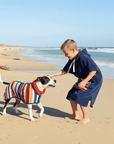 kid wearing a hooded towel playing with a dog that has a matching dog drying coat 