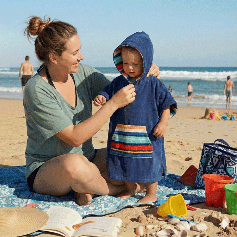 toddler at the beach with his mum, toddler is wearing a hooded towel designed by Dolphin and Dog