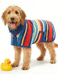 A wet dog wearing a colorful wearable dog towel with a rubber duck on a white background.